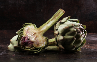 Fresh artichokes on a dark surface.