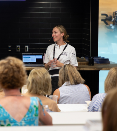 Chef instructor presenting a culinary wellness class to attendees in a classroom.